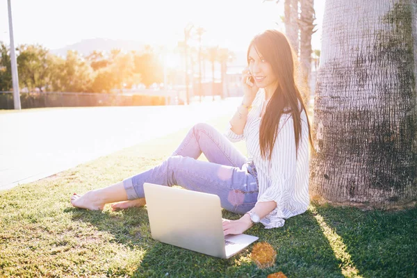 Jonge Vrouw Praten Telefoon Tijdens Het Gebruik Van Een Laptop — Stockfoto