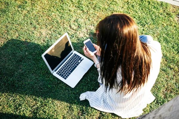 ノート パソコンとスマート フォンを持つ若い女性は晴れた日に公園で破ること — ストック写真