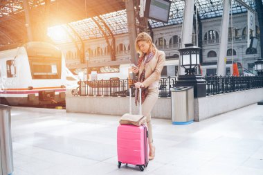 genç çekici işkadını tren istasyonu platformu üzerinde Treni beklerken Smartphone kullanarak