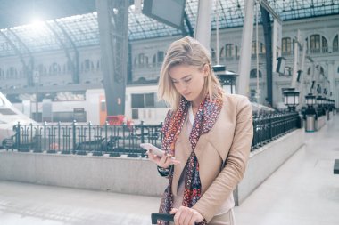 genç çekici işkadını tren istasyonu platformu üzerinde Treni beklerken Smartphone kullanarak