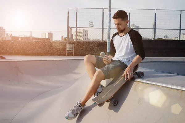 Jongeman Het Bezit Van Een Mobiele Telefoon Zittend Een Skate — Stockfoto