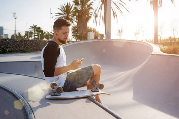 Jongeman Het Bezit Van Een Mobiele Telefoon Zittend Een Skate — Stockfoto