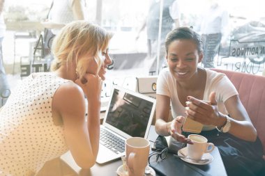 Bir kahve dükkanında dinlenme yaparken fotoğraf bir smartphone bir ekranda izlerken iki kadın hipsters 