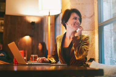 Telefonla konuşurken dizüstü bilgisayar kullanan güzel genç kadın