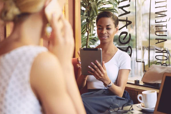 아프리카 여자는 커피숍에서 친구와 디지털 태블릿의 화면을 보고는 — 스톡 사진