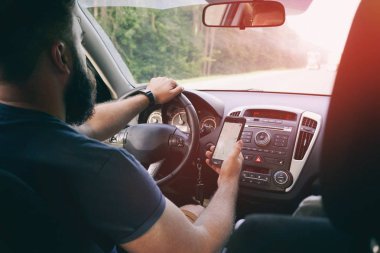 arabada otururken amaçlı hedef bulmak için bir cep telefonu ile bir konumu harita ekranda tutan sakallı sürücü