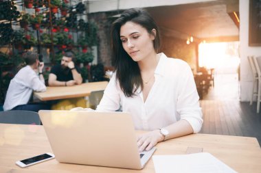 Güzel genç işkadını bir kafede otururken öğle yemeği molası sırasında laptop ile çalışma 