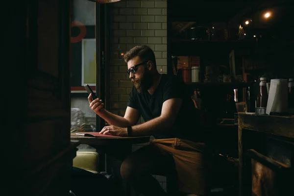 Stilig Skäggig Man Bär Solglasögon Tittar Skärmen Smartphone Coffee Shop — Stockfoto
