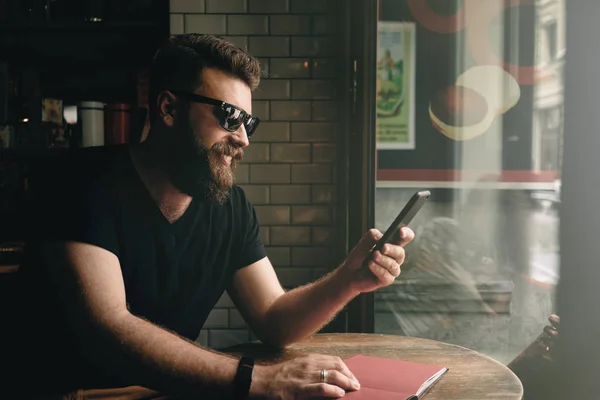 Kjekk Skjeggete Mann Med Solbriller Som Ser Skjermen Til Smarttelefonen – stockfoto