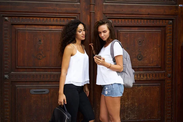 Twee Mooie Jonge Vrouwen Met Smartphone Tegen Houten Straat Deur — Stockfoto