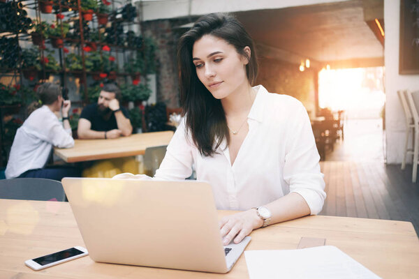 Beautiful young businesswoman working with laptop during the lunch break while sitting in a coffee shop 