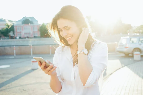 晴れた日に 通りに立っている間手でスマート フォンを保持して美しい若い女性 — ストック写真