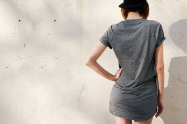 bir gri boş tişört ve siyah beton duvar arka plan üzerinde poz kap giyen güzel genç kadın 
