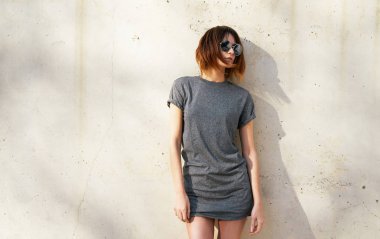 gri boş t-shirt ve arka plan beton duvara karşı poz güneş gözlüğü giyen güzel genç kadın 