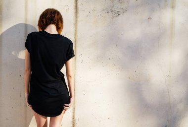 Siyah boş t-shirt arka plan beton duvara karşı poz giyen çekici genç kadın