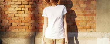 bir beyaz boş t-shirt bir tuğla duvar arka planı poz içinde giyen genç kadın