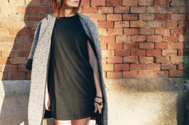 Bir siyah boş T-shirt ve tuğla duvar arka planı poz ceket giyen çekici genç kadın 