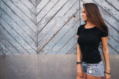 hafif mavi ahşap çit karşı bekleyen boş bir siyah t-shirt güzel genç kadın