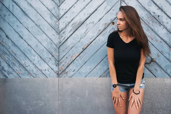 ライト ブルー木製フェンスに対して空白の黒 シャツ立っての美しい若い女性 — ストック写真