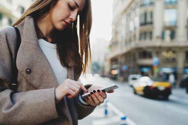 通りを歩きながらスマート フォンを使用してスタイリッシュな服を着ている美しい若い女性 — ストック写真