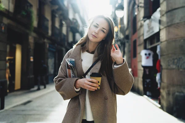 陽気な若い女性を奪うコーヒーと通りを歩いて新聞 — ストック写真