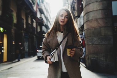 Serbest meslek sahibi erkek coworking alan bir kağıt fincan kahve ve bir gazete onun elinde olacak. İş kadını giyiyor rahat kıyafet açık havada bir bardak kahve ile serbest zaman sırasında rahatlatıcı.