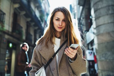 Bir cep telefonu kameraya bakarak onun elinde tutan genç kadın yarım uzunluk portre şehir sokak arka plan bulanık