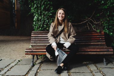 Neşeli çekici genç kadın bir şehir parkı gazete okuma portresi 