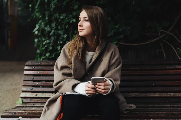 Junge Frau Trendigen Outfit Mit Smartphone Auf Holzbank Freien — Stockfoto