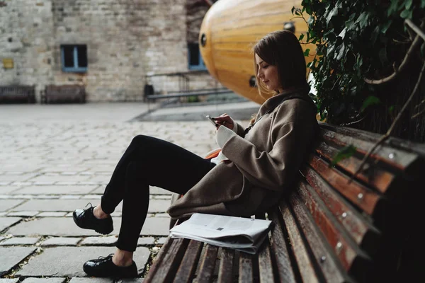 Jovem Mulher Uma Roupa Moda Usando Smartphone Enquanto Sentado Banco — Fotografia de Stock