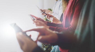 Genç insanların elindeki farklı mobil cihazların yakın plan görüntüsü. Uçuş biletlerini bulmak için internette gezinen bir grup arkadaş ve tatil gezisi için otel. Alete odaklan..