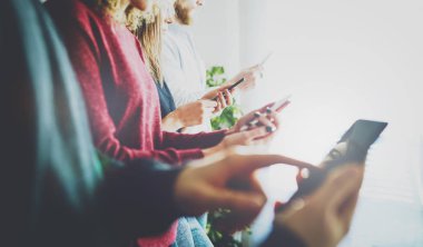 Cep telefonu ve not defteri kullanan bir grup genç erkek ve kadının yan görüntüsü. Mobil cihazlarda internete mesajlaşırken ve sörf yaparken ekranlara dokunan ellerin kırpılmış görüntüsü. 