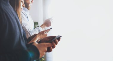 Cep telefonlarını tutan ellerin yan görüntüsü. Hippiler tatil gezisi sırasında harcanan parayı online bankacılık kullanarak paylaşıyorlar. Öğrenciler mobil cihazlarla online oyun oynuyorlar. Aletlere odaklan.