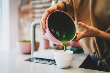 Kahve dükkanında profesyonel barista tarafından yapılan süper doğal kibrit çayı. Bir kadının elleri, fincana dökülmeye hazır bir kibrit çayıyla bir kase tutuyor ve servis ediliyor. Doğu tarzında çay seremonisi..