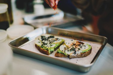 Şef sandviçe balkabağı, chia tohumu, avokado ve armut dilimleri ve çoklu tahıllı çavdar ekmeği ekliyor. Doğal glütensiz malzemelerden yapılan lezzetli vejetaryen yemekleri..