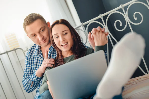 Couple sitting in a room on the bed with laptop — Stock Photo, Image