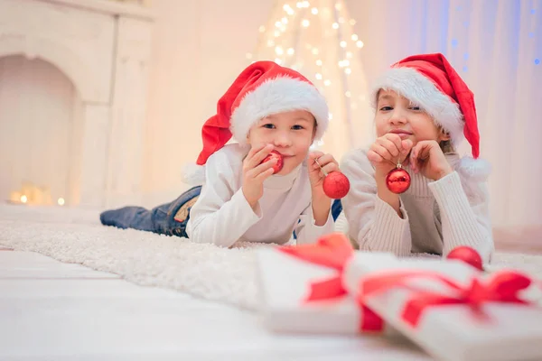 Dos niños en sombrero de Santa con decoraciones navideñas —  Fotos de Stock