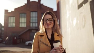 Bir kız kahve içer ve şehir etrafında yürür