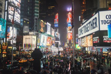 New York Times Meydanı 'ndaki yağmur şemsiyeli insanlar.