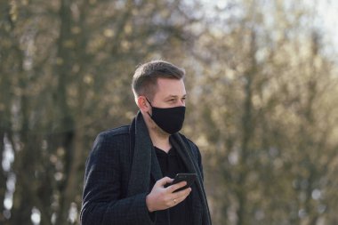 Maskeli adam parkta yürüyor.