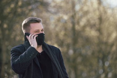 Maskeli adam parkta yürüyor.