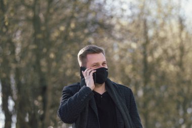 Maskeli adam parkta yürüyor.