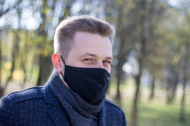 Maskeli adam parkta yürüyor.