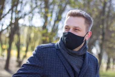 Maskeli adam parkta yürüyor.