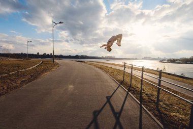 Genç adam dışarıda parkour yapıyor.