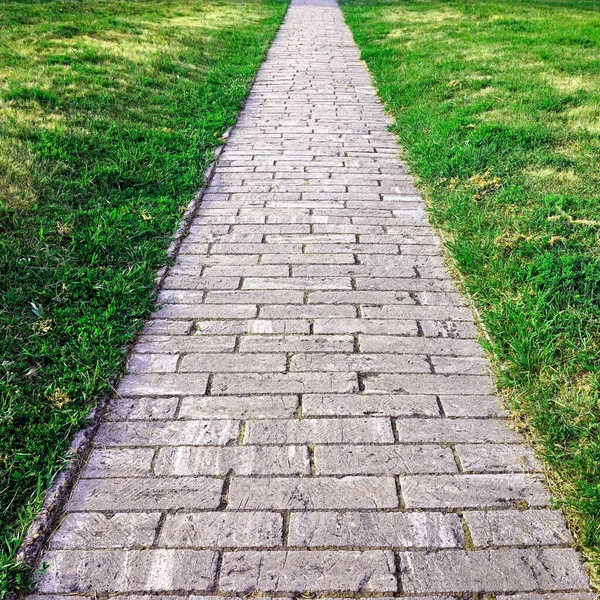 Sidewalk. Rak stig av granit grå kullersten. — Stockfoto
