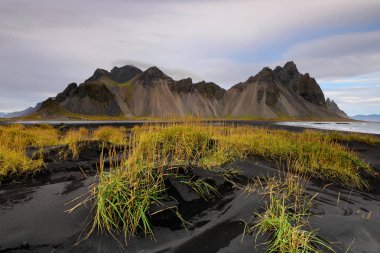 İzlanda'daki Vesturhorn dağ manzarası günbatımında harika. Dağ arka plan ve göl ile siyah kum plaj. Bir ülkenin doğal güzellik tam turistik.