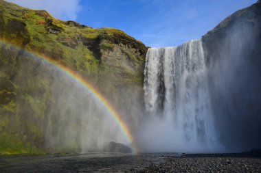 Skogafoss İzlanda'daki en popüler şelale var. Su sis içinde büyük gökkuşağı ile batımında manzara. 