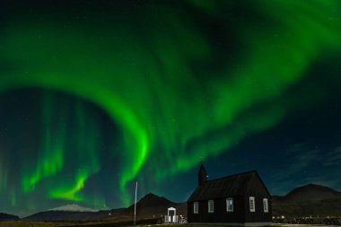 Budir, İzlanda Kuzey ışıkları üzerinde siyah kilise. Aurora Borealis şaşırtıcı bir nightscape içinde. Güzel yeşil ışıklar manzara ile seyahat hedef.