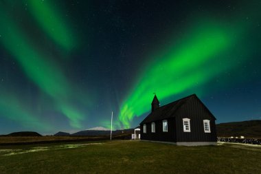 Budir, İzlanda Kuzey ışıkları üzerinde siyah kilise. Aurora Borealis şaşırtıcı bir nightscape içinde. Güzel yeşil ışıklar manzara ile seyahat hedef.